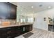 Kitchen with dark cabinets, quartz countertops, gray backsplash, and hardwood-style floors open to living area at 11309 Grand Park Ave, Riverview, FL 33578