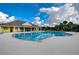 Community pool with ample lounge chairs and umbrellas with the clubhouse in the background at 11309 Grand Park Ave, Riverview, FL 33578