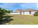 Expansive green backyard with a white fence, lush trees, and the home's exterior at 12310 Streambed Dr, Riverview, FL 33579