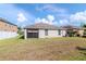 Spacious grassy backyard featuring the rear of a home with a screened-in lanai under a bright cloudy sky at 12310 Streambed Dr, Riverview, FL 33579
