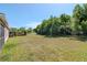 Large grassy backyard bordered by lush green trees and landscaping under a clear blue sky at 12310 Streambed Dr, Riverview, FL 33579