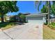 Charming single-story home featuring a two-car garage, well-manicured lawn, and lush tropical landscaping at 12920 Lake Ventana Dr, Tampa, FL 33625