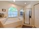 Elegant main bathroom featuring a garden tub with a window, glass shower, and tile surround at 12920 Lake Ventana Dr, Tampa, FL 33625
