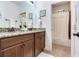 Bright bathroom with granite counters, double sinks, wood cabinets, and neutral ceramic tile at 13008 Eagles Entry Dr, Odessa, FL 33556