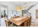 Bright dining room with a long wooden table, staircase with elegant iron railings, and a large wicker light fixture at 13008 Eagles Entry Dr, Odessa, FL 33556