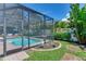 A screened-in pool area features a sparkling pool, patio furniture, and lush landscaping at 13008 Eagles Entry Dr, Odessa, FL 33556