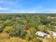 An aerial view of a house with a pool surrounded by lush green trees under a clear blue sky at 1308 W Perdiz St, Tampa, FL 33612