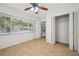 Neutral bedroom features tile flooring, ceiling fan, closet, and window overlooking the front yard at 1308 W Perdiz St, Tampa, FL 33612