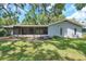 Rear exterior featuring screened in porch and tree covered lawn at 1308 W Perdiz St, Tampa, FL 33612