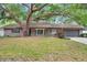 Charming brick home featuring a lovely, large tree, well-maintained lawn and an attached two-car garage at 1308 W Perdiz St, Tampa, FL 33612