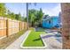 Backyard with lush green putting green, white gravel accents, mature trees, and well-maintained landscaping at 1596 Idle Dr, Clearwater, FL 33756