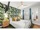 A cozy bedroom features a tropical wallpaper accent wall and sleek ceiling fan at 1596 Idle Dr, Clearwater, FL 33756