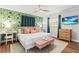 Bedroom boasts a tropical wallpaper accent wall, ceiling fan, and streaming television at 1596 Idle Dr, Clearwater, FL 33756