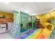 Colorful playroom with custom bunkbeds, climbing wall, slide, and soft rainbow flooring at 1596 Idle Dr, Clearwater, FL 33756