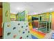 Playroom featuring custom bunkbeds, climbing wall, slide, and soft rainbow flooring at 1596 Idle Dr, Clearwater, FL 33756