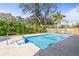 Backyard pool and patio area with lounge chairs, lush landscaping, and a privacy fence at 1596 Idle Dr, Clearwater, FL 33756
