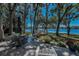 A deck with seating overlooks a large yard, mature trees, and beautiful lake views at 16019 Chastain Rd, Odessa, FL 33556