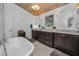 Light-filled bathroom boasting a soaking tub, custom dark cabinetry, and stylish sconce lighting at 16019 Chastain Rd, Odessa, FL 33556