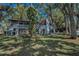 Rear exterior elevation showcasing a home with a deck and stairs, surrounded by trees and lush lawn at 16019 Chastain Rd, Odessa, FL 33556