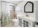 Bright bathroom with white vanity, decorative mirror, and tub with shower featuring a shower curtain at 2217 Stacy Ct, Dunedin, FL 34698