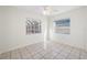 Bright bedroom featuring tiled floors, two windows, a ceiling fan, and white trim at 2217 Stacy Ct, Dunedin, FL 34698