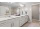 Bright bathroom featuring a long vanity with double sinks, white cabinets, and an extra large mirror at 2577 Buckthorn Loop, North Port, FL 34289
