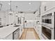 Bright, white kitchen with stainless steel appliances, double oven, quartz counters and modern pendant lighting at 2577 Buckthorn Loop, North Port, FL 34289