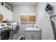 Bright laundry room features modern washer and dryer, white cabinetry and sink with beautiful marble countertops at 3117 W Lawn Ave, Tampa, FL 33611