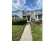 A colorful two-story townhome with a landscaped front yard and a concrete walkway under a blue cloudy sky at 3441 Santa Rita Lane, Land O Lakes, FL 34639