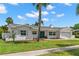 Charming white brick home with a well-manicured lawn, palm trees and a light gray roof at 3945 Versailles Dr, Tampa, FL 33634