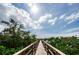 Scenic wooden walkway leading to waterfront homes, lined with lush green trees and bright blue skies at 4516 Seagull Dr # 615, New Port Richey, FL 34652