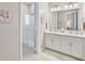 Bright bathroom with double vanity, framed mirrors, and glass enclosed walk-in shower at 5313 Windy Grove Dr, Wimauma, FL 33598