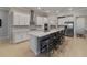Spacious kitchen boasts white cabinets, stainless steel appliances, large island with bar seating, and modern finishes at 5313 Windy Grove Dr, Wimauma, FL 33598
