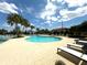 Community pool with palm trees and lounge chairs under a sunny, partly cloudy sky at 5313 Windy Grove Dr, Wimauma, FL 33598