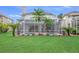 Spacious backyard featuring a screened-in pool, palm trees, and lush greenery at 5403 Avenal Dr, Lutz, FL 33558