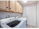 Well-lit laundry room featuring a washer, dryer, and overhead storage cabinets at 5403 Avenal Dr, Lutz, FL 33558