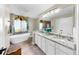 Elegant bathroom with double vanity, soaking tub, and a large mirror providing ample light at 613 Fort Duquesna Dr, Sun City Center, FL 33573