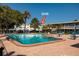 Refreshing community pool with lounge chairs and tables surrounded by lush tropical landscaping at 6161 Gulf Winds Dr # 338, St Pete Beach, FL 33706