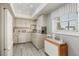 Bright kitchen with white cabinets, appliances, and gray-toned wood-look flooring, complemented by a window and checkered curtains at 6161 Gulf Winds Dr # 338, St Pete Beach, FL 33706