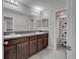 Bathroom featuring double sinks with dark wood cabinets and a shower with a decorative fish-themed curtain at 6325 Shore Vista Pl, Apollo Beach, FL 33572