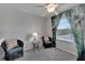 Bright bedroom featuring cozy chairs, a ceiling fan, and a window with nature-themed curtains at 6325 Shore Vista Pl, Apollo Beach, FL 33572