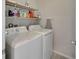Functional laundry room with appliances, shelving for storage, and neutral colors at 6325 Shore Vista Pl, Apollo Beach, FL 33572