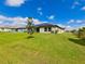Expansive backyard featuring lush green grass, a young tree, and a view of the home's exterior at 6416 Cobble Bliss St, Zephyrhills, FL 33541