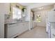 Functional kitchen with white cabinets, dishwasher, and view of the laundry area at 6936 77Th N Ter, Pinellas Park, FL 33781