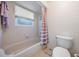 Clean bathroom featuring a tub/shower combo, tiled walls, and a bright window at 9008 Quail Creek Dr, Tampa, FL 33647