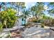 Inviting backyard features white rock, brick walkway, vibrant foliage, and a small storage shed with bright blue door at 9107 Bay Ne St, St Petersburg, FL 33702