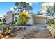 Charming home exterior with stone accents, mature landscaping, covered parking, and a circular window detail at 9107 Bay Ne St, St Petersburg, FL 33702