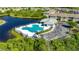 Aerial view of a community pool, surrounded by landscaping, a lake, parking and building with metal roof at 9516 Amberdale Ct # 202, Riverview, FL 33569