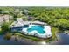 Aerial view of a community pool area with lounge chairs, umbrellas, and landscaping near a small lake at 9516 Amberdale Ct # 202, Riverview, FL 33569