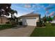 Charming home featuring a two-car garage, well-manicured lawn, and a beautifully landscaped front yard with mature trees at 11225 Godwit Ct, New Port Richey, FL 34654